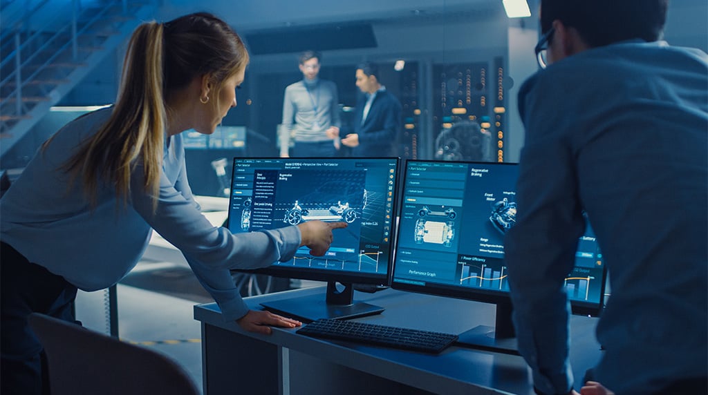Two people working at computer with car graphics and lab in background 