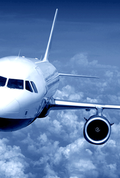 The view from the front pilot's side looking backwards, of a modern passenger jet flying above a bank of clouds.